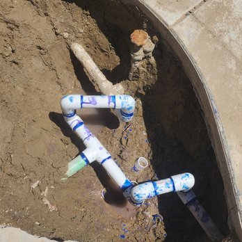 Underground PVC water line installation with fittings visible in an excavated trench